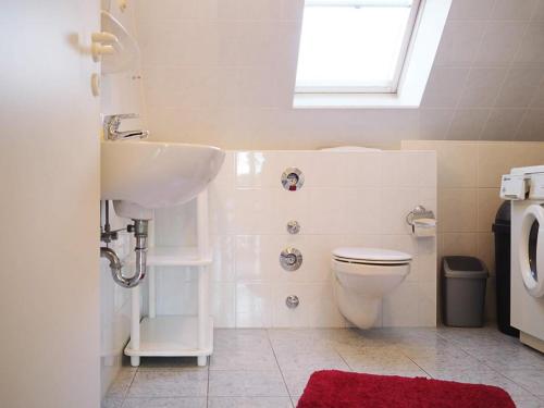 ein Bad mit einem Waschbecken, einem WC und einem Fenster in der Unterkunft Apartments Haus an der Stems 30 & 31 in Prerow