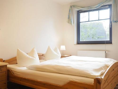 Schlafzimmer mit einem Bett mit weißer Bettwäsche und einem Fenster in der Unterkunft Haus Komoran Wohnung 3 in Prerow