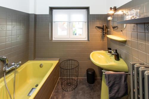 a bathroom with a yellow tub and a sink at LE ROESSELMANN in Turckheim