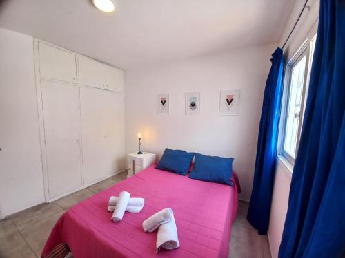 Un dormitorio con una cama rosa con toallas. en La Gema apartamento en Mendoza