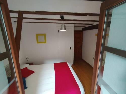 a bedroom with a white bed with a red blanket at Apartamento centro Benasque in Benasque