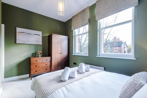 a bedroom with a white bed and two windows at Hilltop Serviced Apartments - Stockport in Stockport