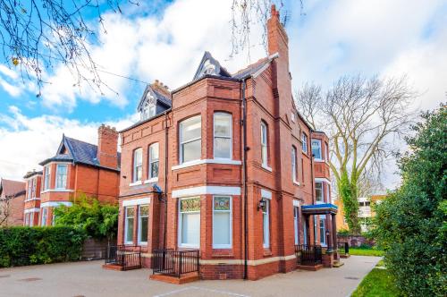 a red brick house with white windows on a street at Hilltop Serviced Apartments - Stockport in Stockport