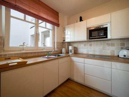 cocina con armarios blancos, fregadero y ventana en Ferienwohnung 560 in der Villa Gudrun en Binz