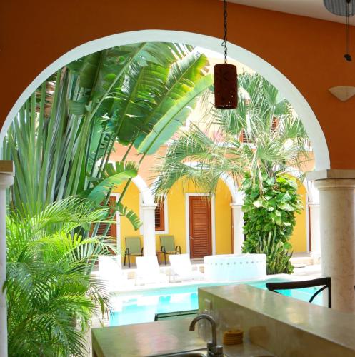 an archway in a restaurant with a pool and palm trees at Merida Santiago Hotel Boutique in Mérida