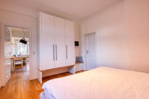 Habitación blanca con cama y escritorio en Landhaus am Ufer - Wohnung 2, en Heiligenhafen