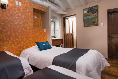 クスコにあるLO NUESTRO Houseのベッドが2つと壁があるホテルの部屋