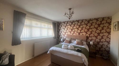 um quarto com uma cama com uma parede floral em Spacious 5 bedroom, 2 Living Room, Games Room em Wolverhampton