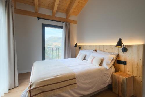 a bedroom with a large bed with a large window at Masia Mateu de l'Agustí in Llimiana