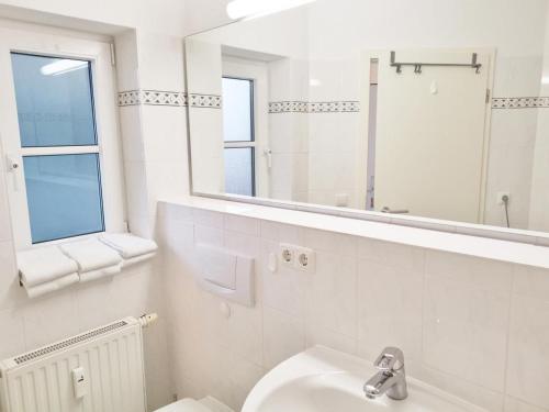 een witte badkamer met een wastafel en een spiegel bij Apartmentvermittlung Mehr als Meer - Objekt 74 in Niendorf
