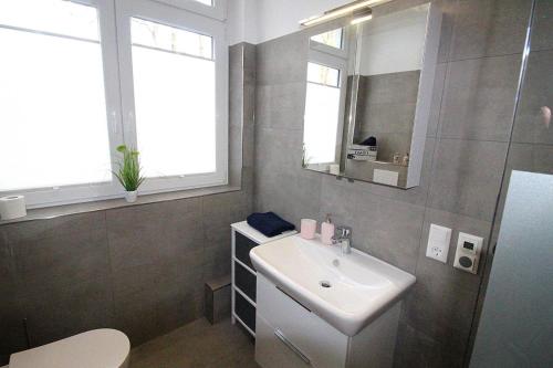 W łazience znajduje się biała umywalka i lustro. w obiekcie Appartementvermittlung Mehr als Meer Objekt 50 w mieście Timmendorfer Strand