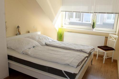 a white bed in a room with a window at Apartmentvermittlung Mehr als Meer - Objekt 24 in Niendorf
