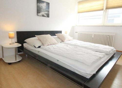 a large bed in a bedroom with a lamp on a table at Apartmentvermittlung Mehr als Meer - Objekt 8 in Niendorf