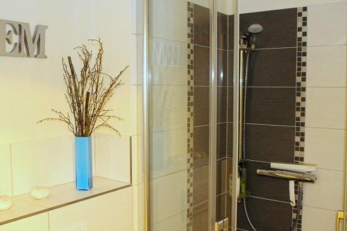 a bathroom with a shower and a blue vase with a plant at Apartmentvermittlung Mehr als Meer - Objekt 78 in Niendorf