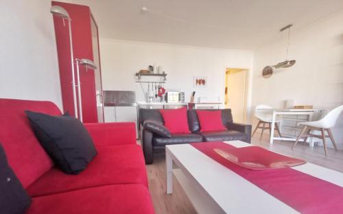 a living room with red and black couches and a kitchen at Apartmentvermittlung Mehr als Meer - Objekt 77 in Niendorf