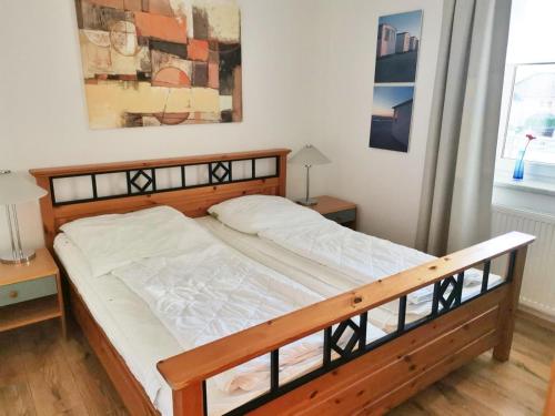 a bedroom with a bed with a wooden frame and a window at Apartmentvermittlung Mehr als Meer - Objekt 9 in Niendorf