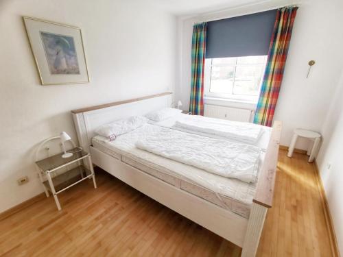 - une chambre avec un lit blanc et une fenêtre dans l'établissement Apartmentvermittlung Mehr als Meer - Objekt 16, à Niendorf
