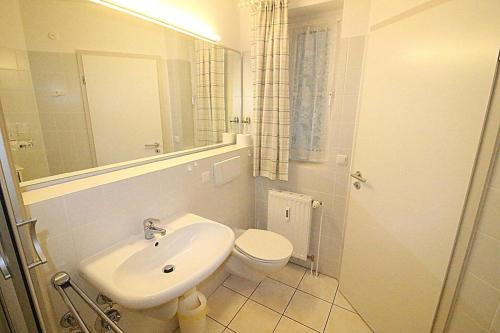 La salle de bains est pourvue d'un lavabo, de toilettes et d'un miroir. dans l'établissement Apartmentvermittlung Mehr als Meer - Objekt 16, à Niendorf