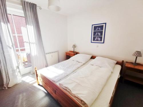 Bett in einem Zimmer mit einem großen Fenster in der Unterkunft Apartmentvermittlung Mehr als Meer - Objekt 10 in Niendorf
