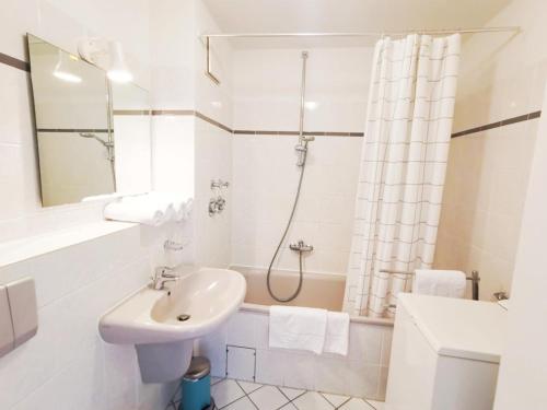 ein weißes Bad mit einem Waschbecken und einer Dusche in der Unterkunft Apartmentvermittlung Mehr als Meer - Objekt 10 in Niendorf