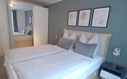 Un dormitorio con una cama con sábanas y almohadas blancas. en Apartmentvermittlung Mehr als Meer - Objekt 73, en Niendorf