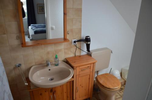 ein Badezimmer mit einem Waschbecken, einem WC und einem Spiegel in der Unterkunft Ferienwohnung Herzmuschel in Cuxhaven