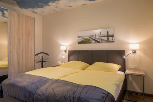 1 dormitorio con 1 cama grande con almohadas amarillas en FEWO Spiekeroog, en Bad Zwischenahn
