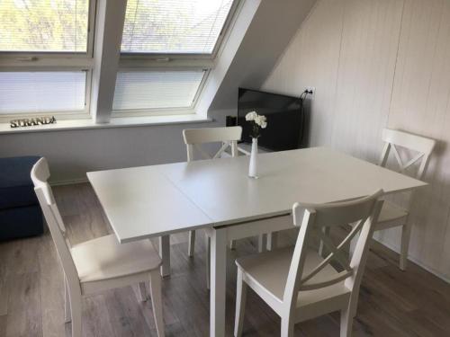 een witte tafel en stoelen in een kamer met ramen bij Ferienwohnung Ankerplatz in Cuxhaven