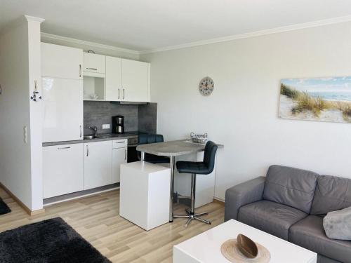 ein Wohnzimmer mit einem Sofa und einem Tisch sowie eine Küche in der Unterkunft Baltic Nr. 21 in Scharbeutz