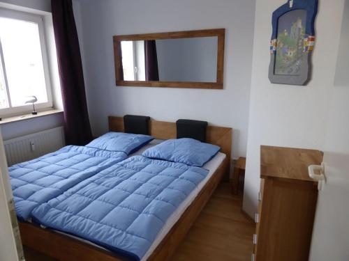 a bedroom with a bed with blue pillows and a mirror at Witthus Nr. 16 in Scharbeutz