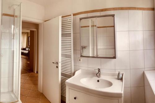 ein weißes Badezimmer mit einem Waschbecken und einem Spiegel in der Unterkunft Turmresidenz App. 3 in Scharbeutz