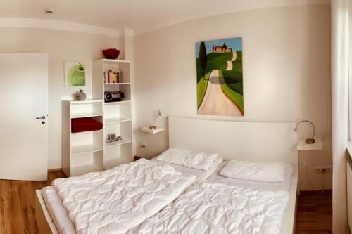 ein Schlafzimmer mit einem weißen Bett und einem Gemälde an der Wand in der Unterkunft Turmresidenz App. 3 in Scharbeutz
