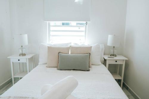 - un lit blanc avec des oreillers blancs et une fenêtre dans l'établissement Casita Style Apt 3 w/ Sofa Bed & Patio @ Santurce, à San Juan