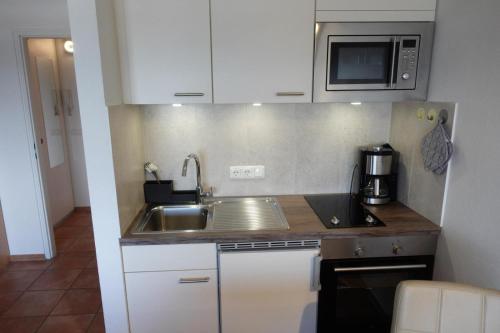 a small kitchen with a sink and a microwave at Ferienwohnung Sprotte in Damp