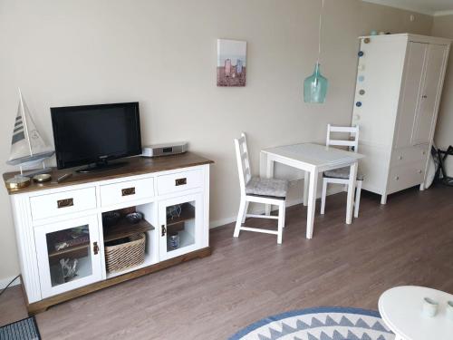 sala de estar con TV, mesa y sillas en Apartment Fördeblick, en Damp