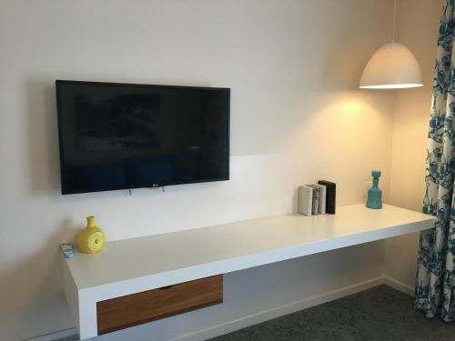 a living room with a tv on a wall at The Beverly Laurel Hotel at West Hollywood in Los Angeles