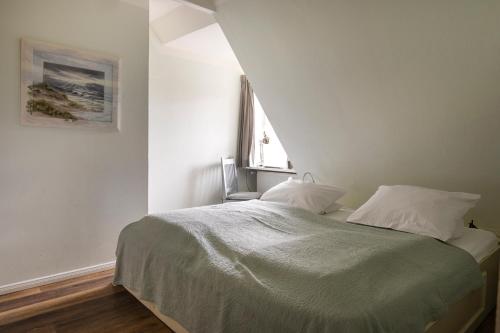 a white bedroom with a bed with a window at Kutscherhaus - Kutscher Karl in Manhagen