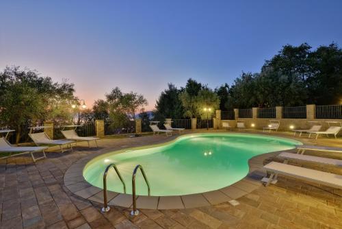 uma piscina à noite com cadeiras e uma mesa em Villa Elaia em Santa Maria di Castellabate