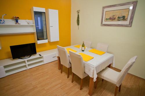 uma sala de jantar com uma mesa com cadeiras e uma televisão em Apartment Anka em Bibinje
