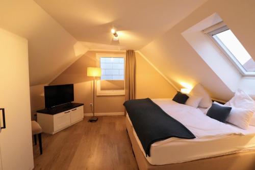 um quarto no sótão com uma cama e uma televisão em Apartmenthuus König em Norderney