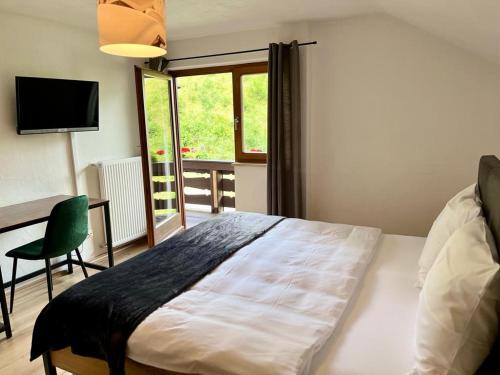 1 dormitorio con cama, escritorio y ventana en Alpenlodge am Waldrand in Grainau en Grainau