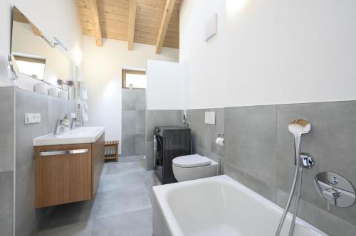 ein Badezimmer mit einer Badewanne, einem WC und einem Waschbecken in der Unterkunft Ferienhaus K4 in Garmisch-Partenkirchen in Garmisch-Partenkirchen