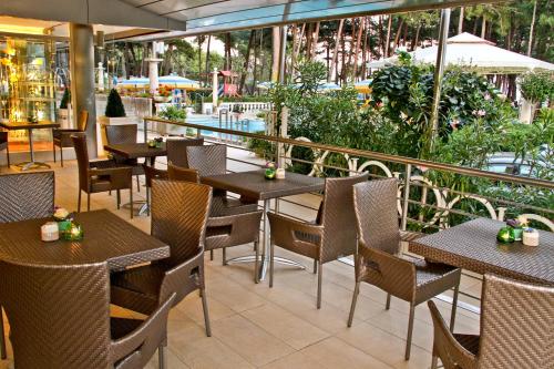 a restaurant with tables and chairs and a balcony at Hotel Colorado in Lignano Sabbiadoro