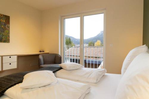 two beds in a bedroom with a large window at Ferienwohnungen Friedenshöhe in Oberammergau in Oberammergau