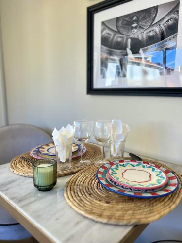 - une table avec deux assiettes et des verres à vin dans l'établissement Studio cosy à Cannes 18 m² avec jardin privé 1 steampod, à Cannes