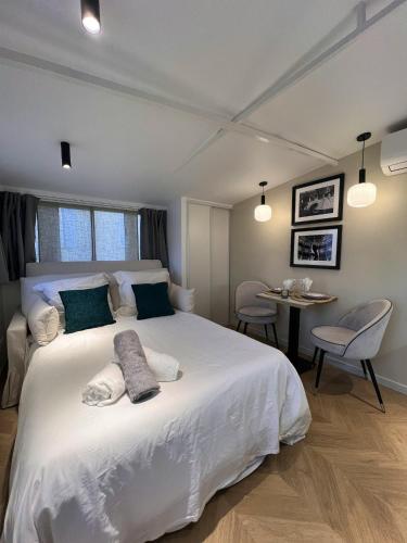 - une chambre avec un lit blanc, une table et des chaises dans l'établissement Studio cosy à Cannes 18 m² avec jardin privé 1 steampod, à Cannes
