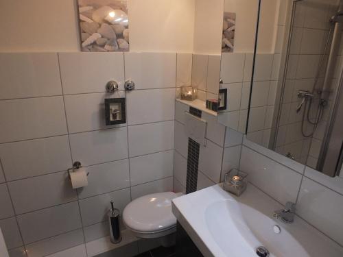 a white bathroom with a toilet and a sink at Watten-Blick 1 in Cuxhaven