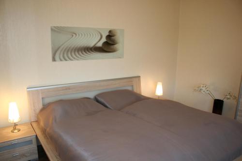 a bedroom with a bed with two lamps and a painting at Watten-Blick 1 in Cuxhaven