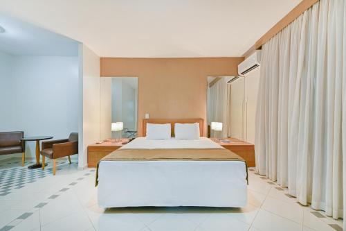 a bedroom with a large bed and a desk at Hotel Nacional Inn Cuiabá in Cuiabá