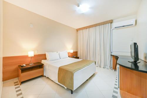 a hotel room with a bed and a flat screen tv at Hotel Nacional Inn Cuiabá in Cuiabá